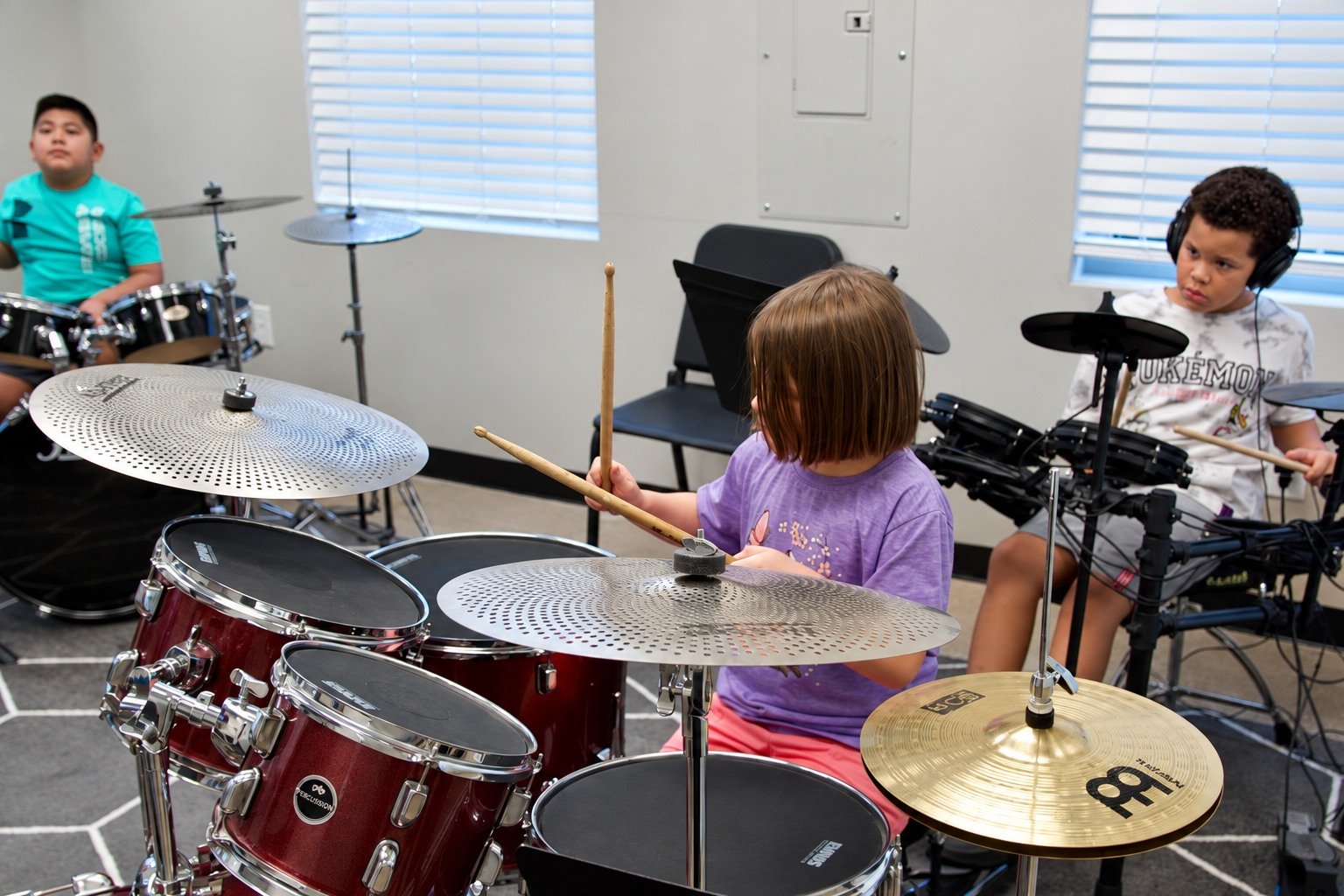 Three Thrive students learning together on acoustic and electronic drum kits