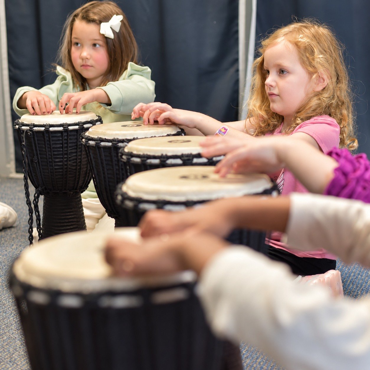 Young children exploring hand drums together at Thrive Creative Arts